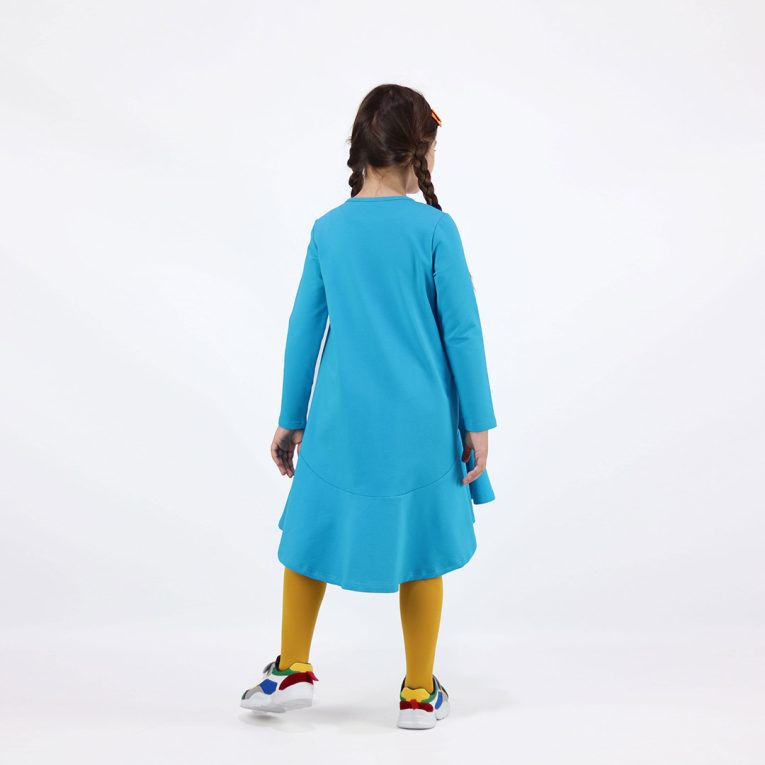 Loose dress is a loose fit dress, that goes wider to the bottom. It is longer on the back with a wide frilled trim at the bottom. Dress is in blue colour. Children, 3 -10 yrs. BonnyJoy, wearing, back, second image