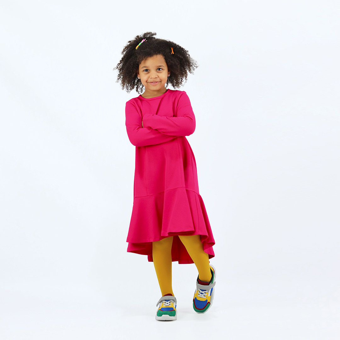 Loose dress is a loose fit dress, that goes wider to the bottom. It is longer on the back with a wide frilled trim at the bottom. Dress is in raspberry colour. Children, 3 -10 yrs. BonnyJoy - wearing, in front, second image