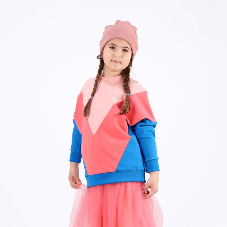 Batwing sweatshirt is a loose fit top with triangular form color blocks. It comes in a combo of three colours - powder, salmon and deep blue. Front view. Children, 3 -10 yrs. BonnyJoy