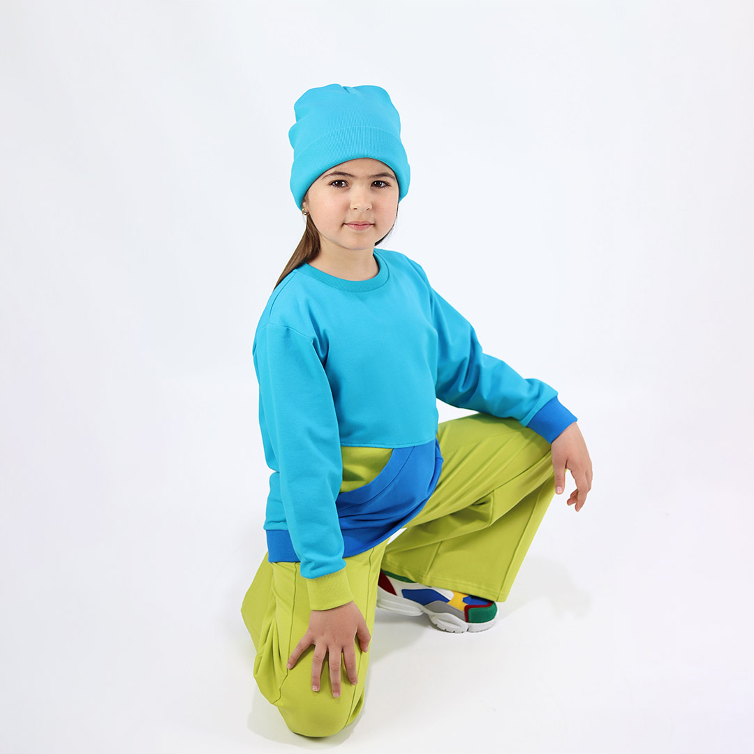 Big pocket sweatshirt is a regular fit top with an asymmetrical big pocket in front. A colour block design that comes in a combo of three colours - electric blue, deep blue, bright lime. Side view, a girl dressed. Children, 3 -10 yrs. BonnyJoy