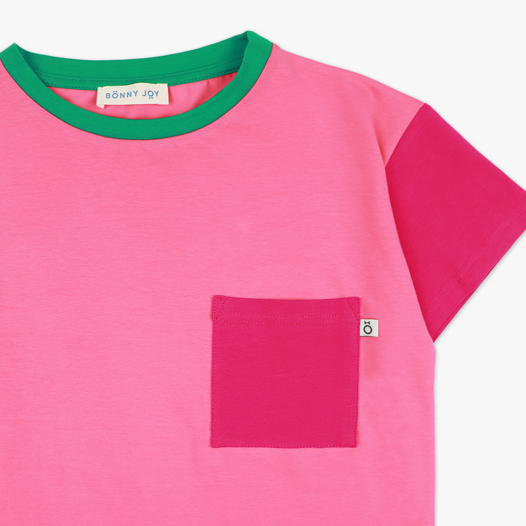 Our colour block t-shirt is a loose fit top with square pocket on the left and a little longer on the back. The front and the back in pink colour, right sleeve in bright lime, left sleeve and the pocket - in raspberry. On the neck - green colour. Front view, close-up. Children, 3 -10 yrs. BonnyJoy