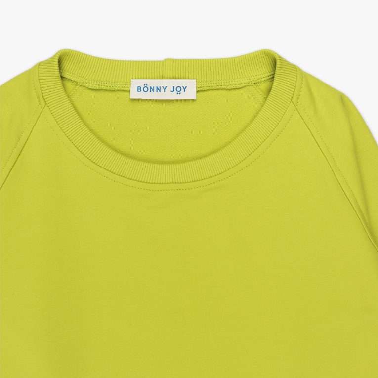 Cylinder dress is a one-colour loose fit dress with round pockets aside and a little longer on the back in bright lime colour. Front view, close-up. Children, 3 -10 yrs. BonnyJoy