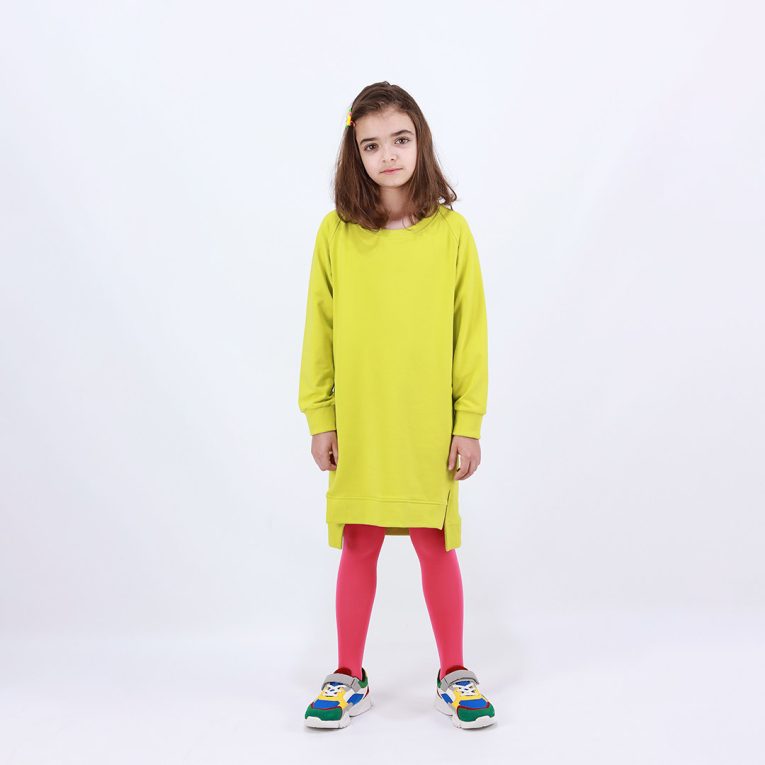 Cylinder dress is a one-colour loose fit dress with round pockets aside and a little longer on the back in bright lime colour. Front view. Children, 3 -10 yrs. BonnyJoy