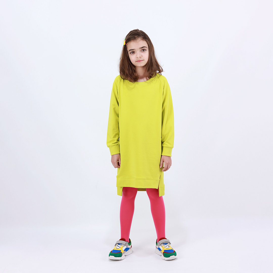 Cylinder dress is a one-colour loose fit dress with round pockets aside and a little longer on the back in bright lime colour. Front view. Children, 3 -10 yrs. BonnyJoy
