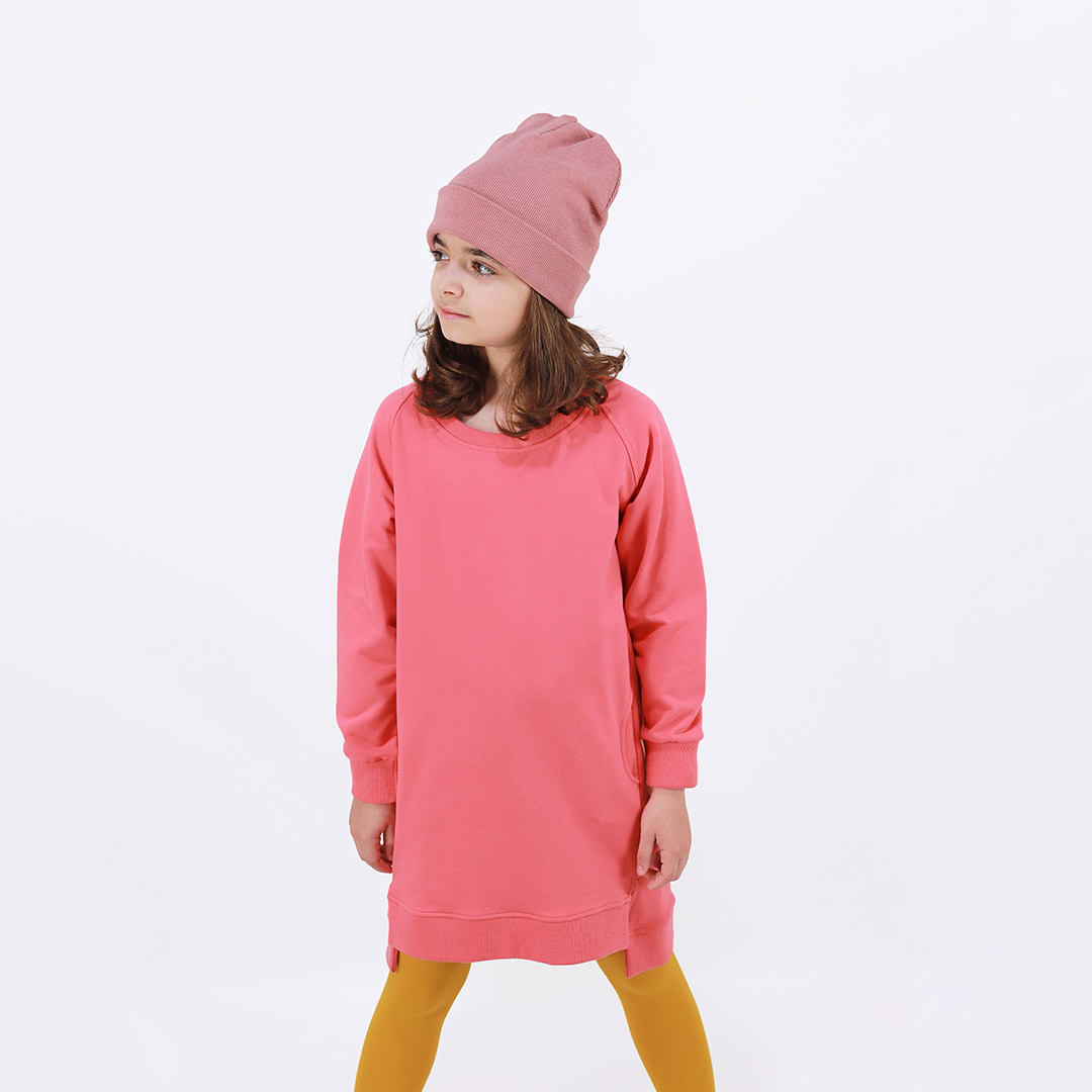 Cylinder dress is a one-colour loose fit dress with round pockets aside and a little longer on the back in salmon colour. Front view. Children, 3 -10 yrs. BonnyJoy