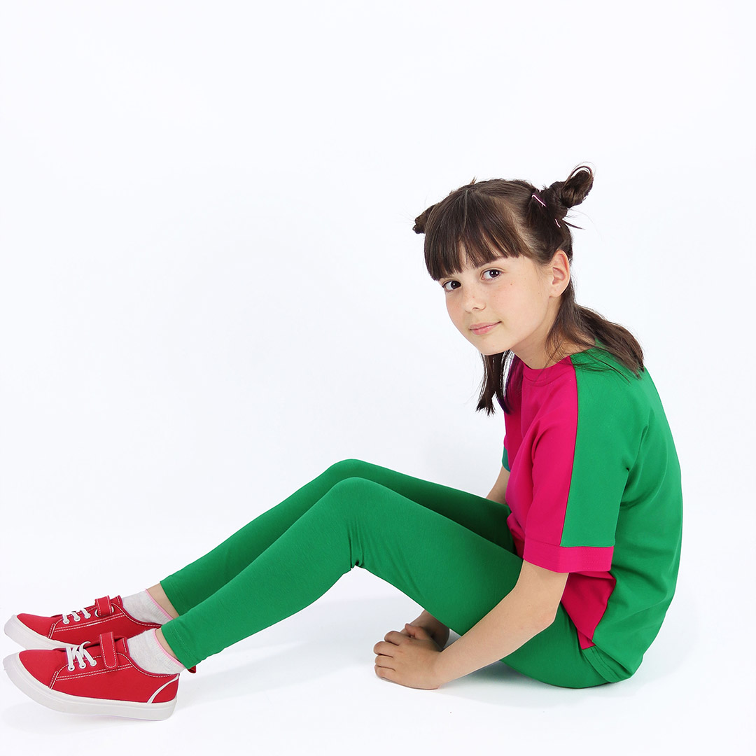 Joyful leggings are absolutely classic leggings in green colour. Side view, a girl sitting. Children, 3 -10 yrs. BonnyJoy