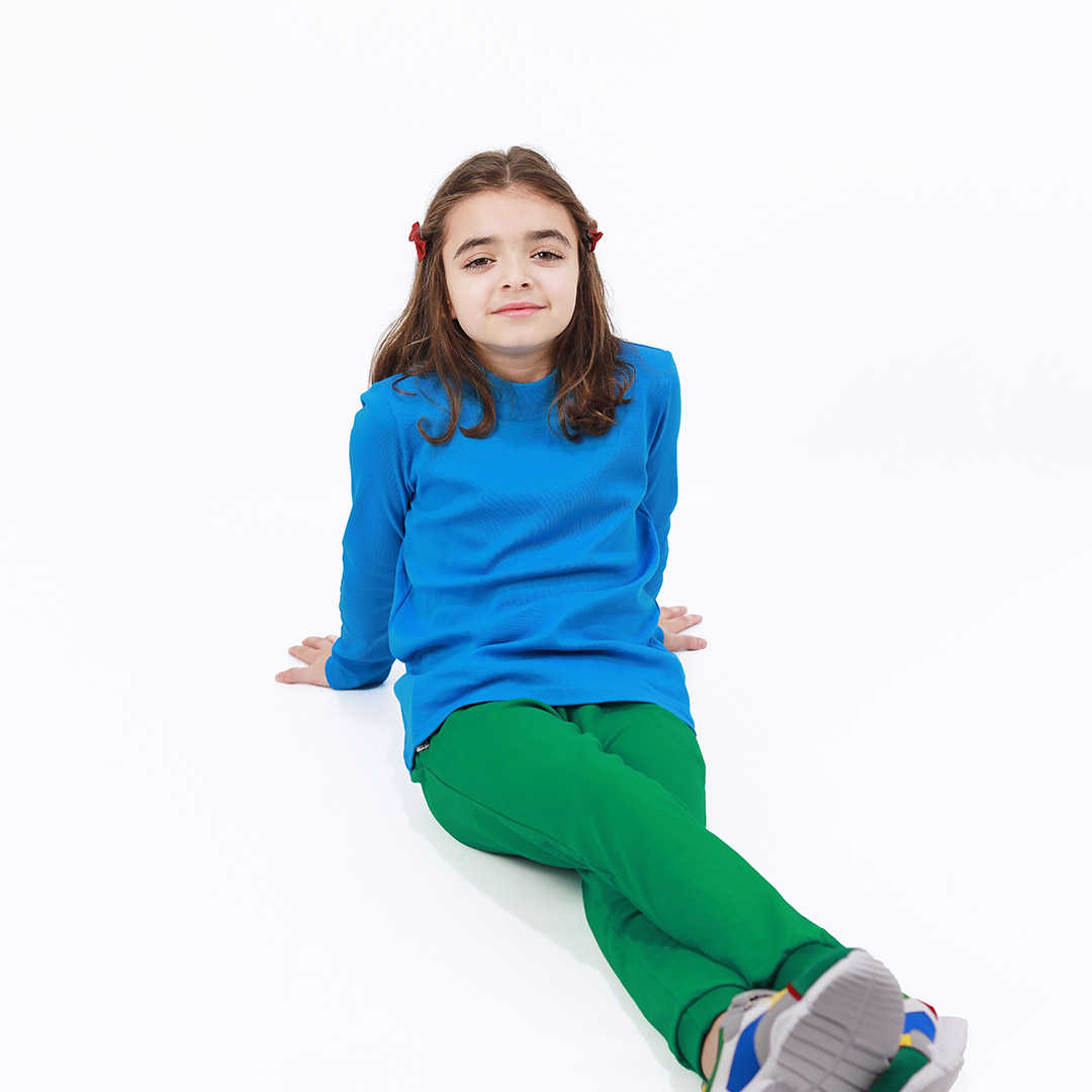 Turtleneck loose top is a classic top in blue colour. Front view, a girl sitting. Children, 3 -10 yrs. BonnyJoy