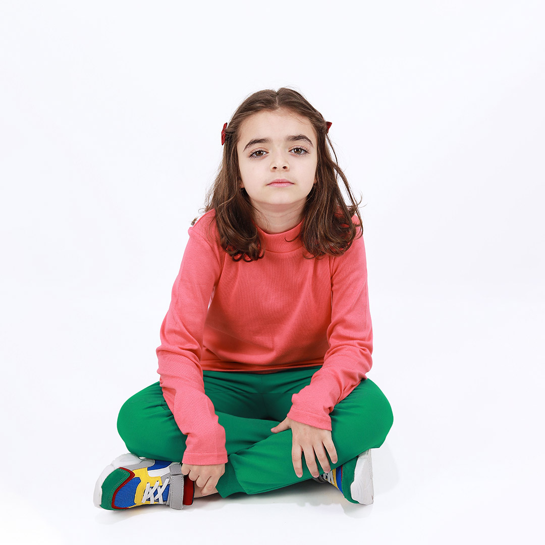 Turtleneck loose top is a classic top in salmon colour. Front view, a girl sitting. Children, 3 -10 yrs. BonnyJoy