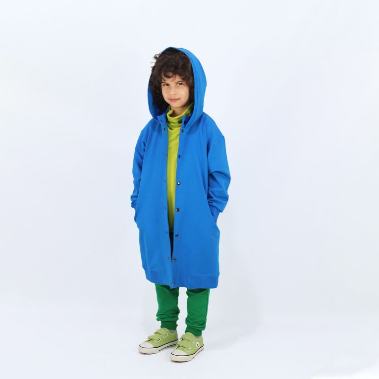 Long buttoned hoodie has a straight loose fit and minimalist design in deep blue colour. It closes up with snap buttons and features hign ribbed neck and ribbed hand cuffs and bottom hem. Front view, a boy standing. Children, 3 -10 yrs. BonnyJoy