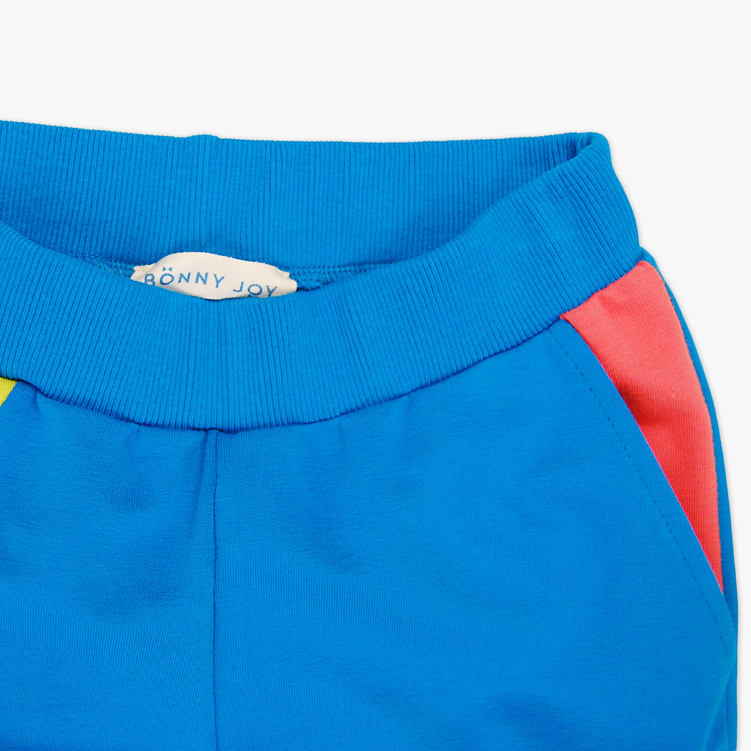Slim Fit Colour Block Joggers are a pair of sweatpants in deep blue with two Italian type side pockets in different colours - bright lime and salmon. It features ribbed waist and cuffs. Front view, close-up. Children, 3 -10 yrs. BonnyJoy