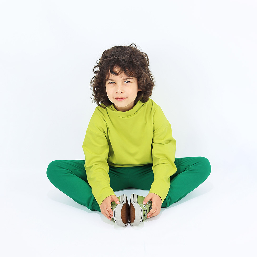 Slim fit joggers is a pair of sweatpants with two Italian type side pockets, ribbed waist and cuffs. The whole pair is in one distinctive colour - green. Front view, sitting. Children, 3 -10 yrs. BonnyJoy