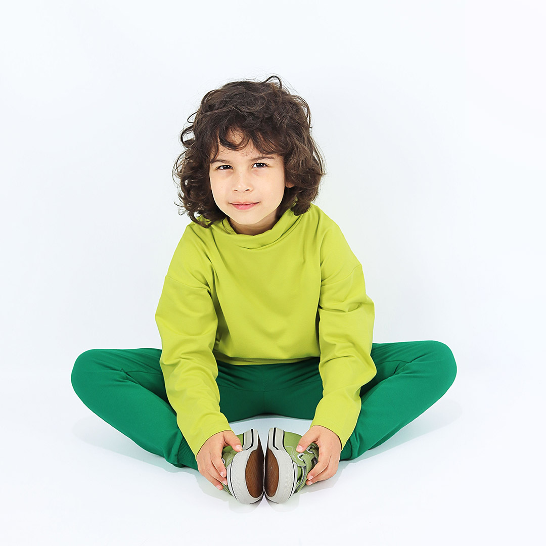 Turtleneck loose top is a classic top loose on the neck in bright lime colour. Front view, a boy sitting. Children, 3 -10 yrs. BonnyJoy