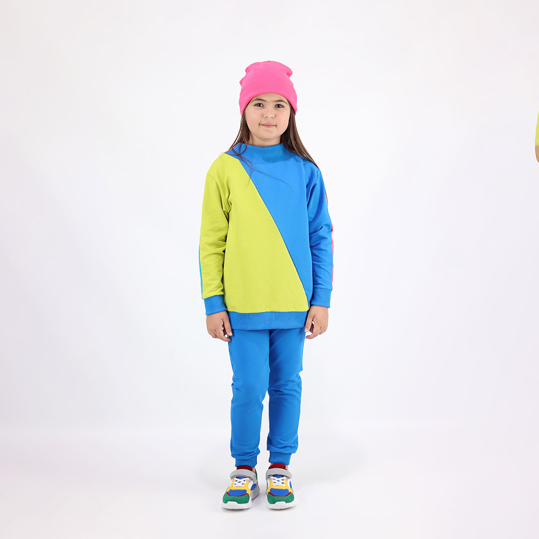 Two-Way Sweatshirt you could wear back on front and the way round. Mix of colours on both sides and diagonal cut on the front and the back. On one side - one sleeve and one diagonal half - salmon, the other sleeve and the other diagonal half - electric blue. On the other side - one sleeve and half - bright lime and the other sleeve and other half - deep blue. Front view, a girl standing. Children, 3 -10 yrs. BonnyJoy