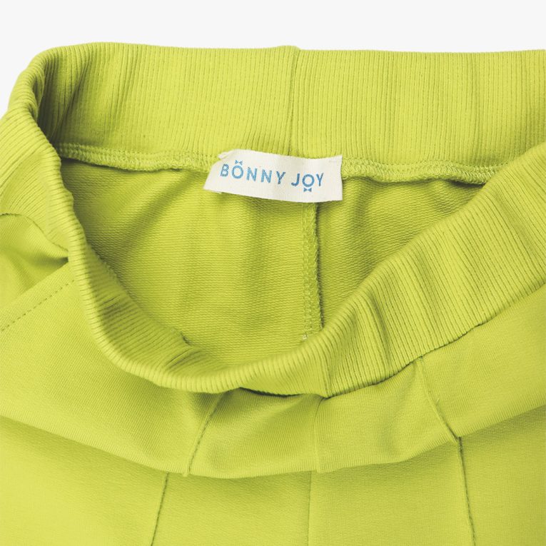 Wide leg pants with an edge hem in front and ribbed waist. Loose fit pants in bright lime colour. Front view, close-up. Children, 3 -10 yrs. BonnyJoy