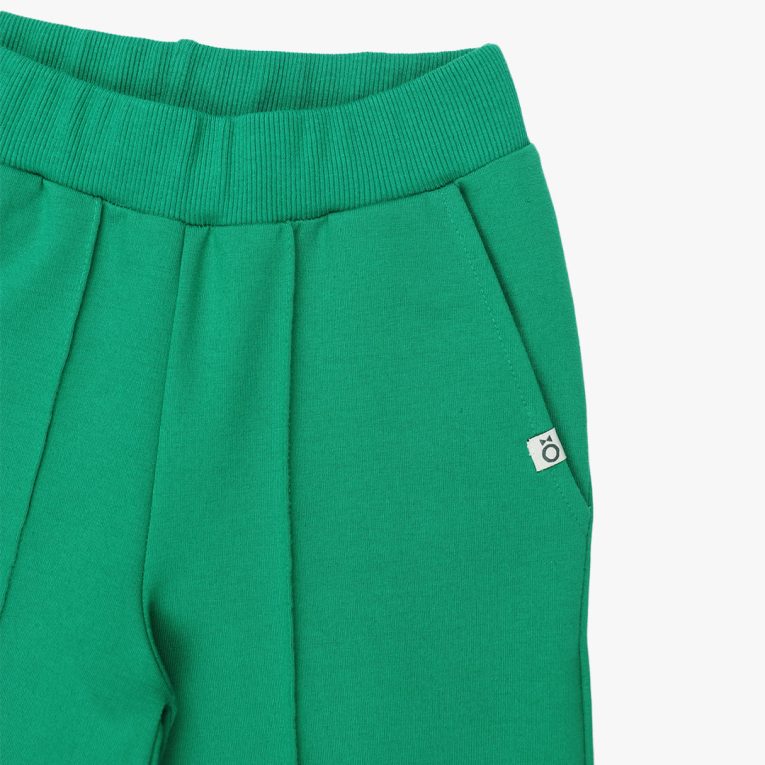 Wide leg pants with an edge hem in front and ribbed waist. Loose fit pants in green colour. Front view, close-up. Children, 3 -10 yrs. BonnyJoy